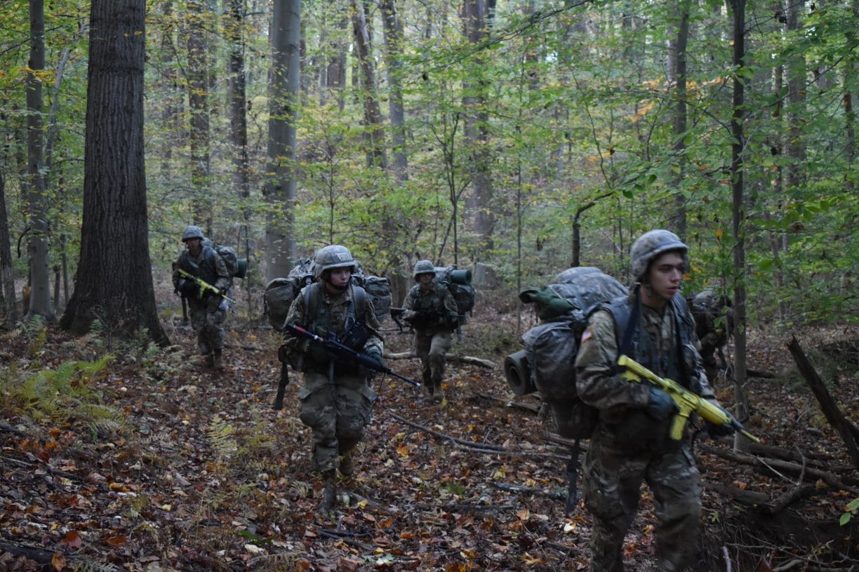 Cadets conducting situational training exercise, patrolling in the woods.