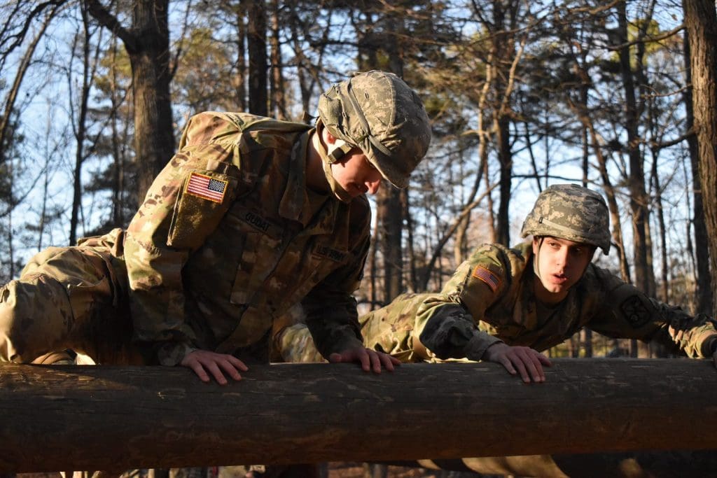 cadets climbing over a log