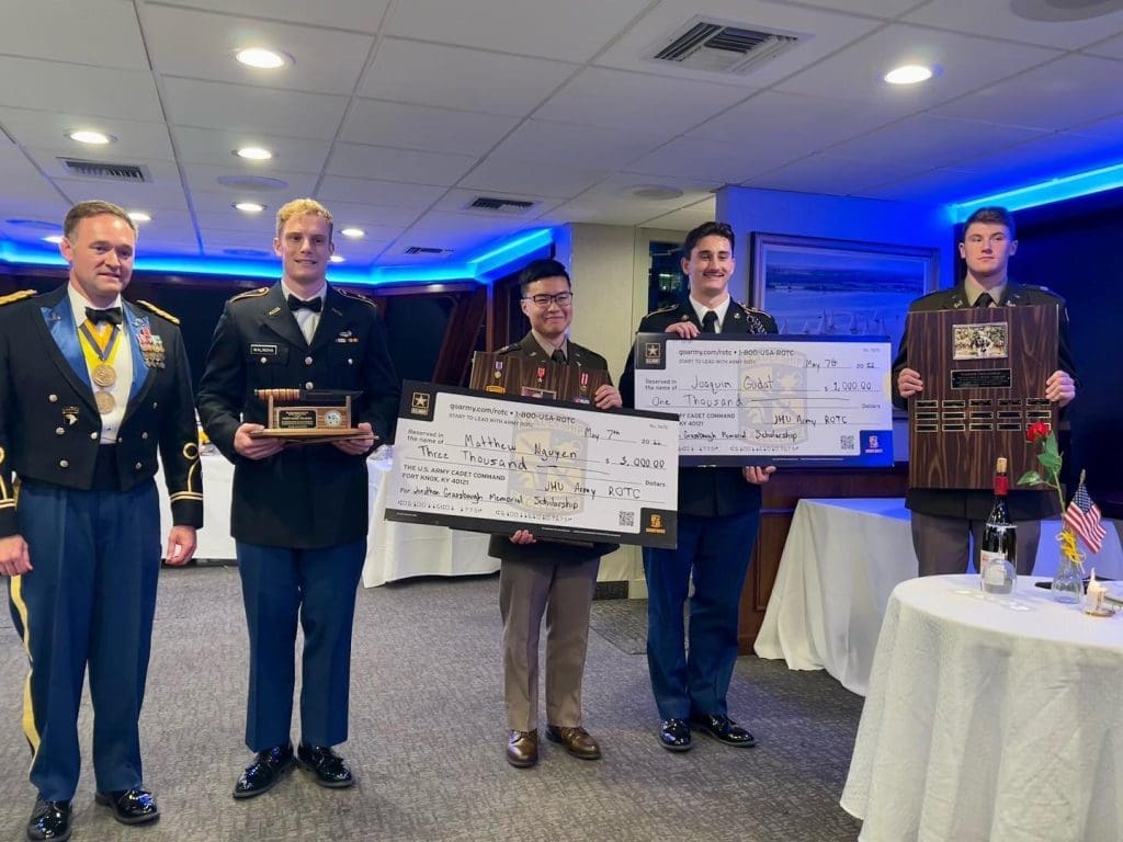 five cadets, two holding checks and one a plaque