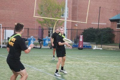 people in ROTC gear on a football field with a frisbee