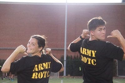two cadets pointing to "army ROTC" written on the back of their shirts