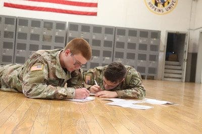 two cadets on the floor writing on papers