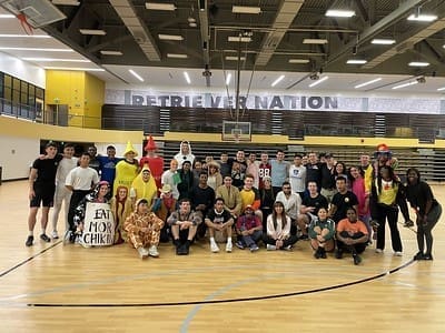 group of people grouped in a gym under a banner saying "retriever nation"
