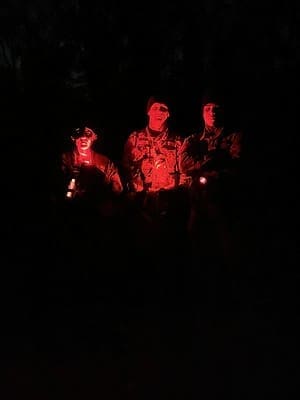 three people in the dark, their faces lit red