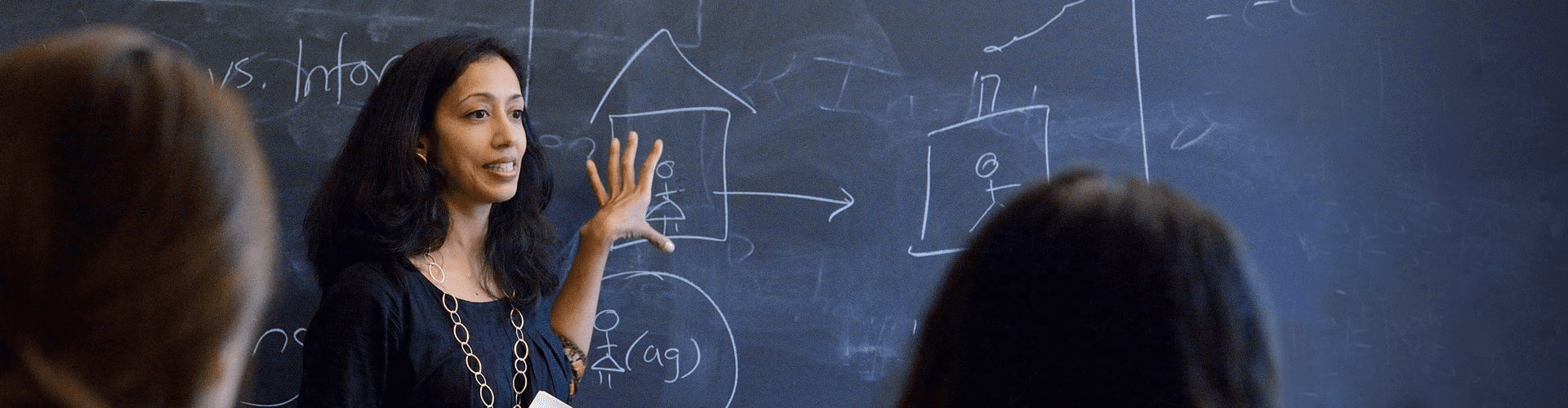Professor pointing to writing on a chalkboard