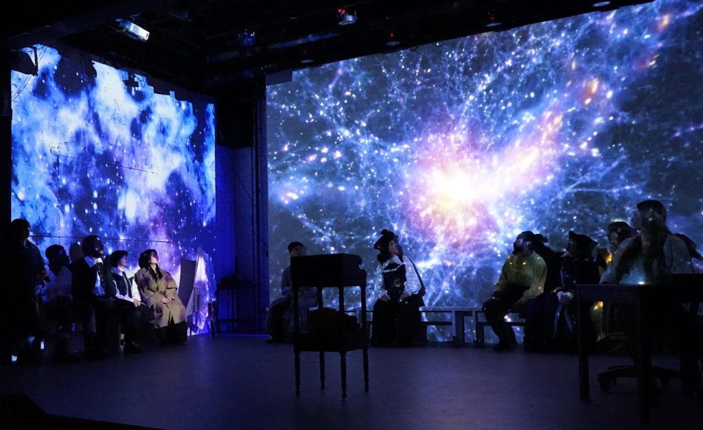 Webb telescope image projected onto stage with actors.