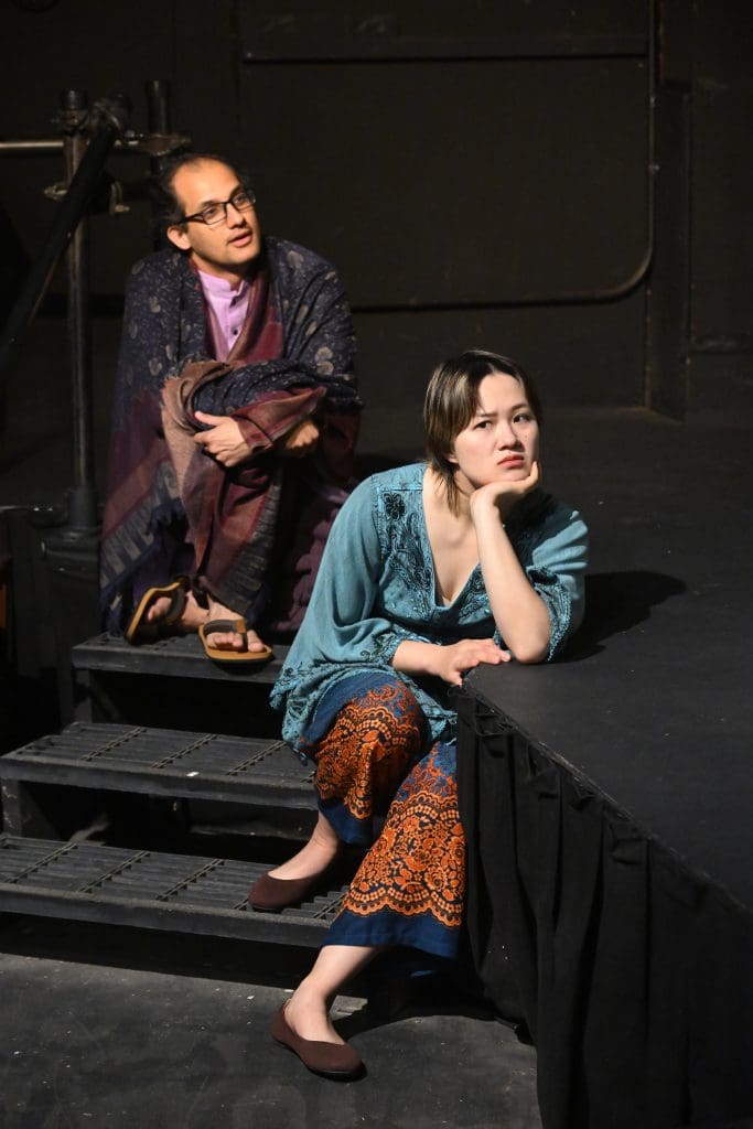 Two people, in colorful clothing, sit on stairs.