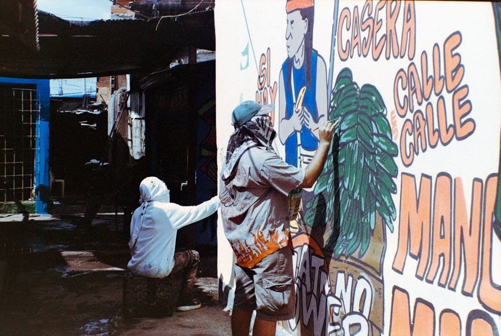 Two people spray painting a wall in a city
