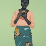 a painting by Amy sherald off a woman with dark hair and braids holding a Pentax camera wearing a salmon colored long sleeve shirt and a floral patterned teal skirt on a green background