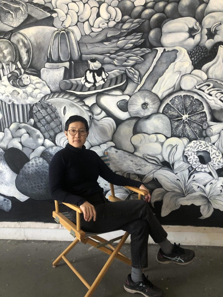 tae hwang portrait - girl with short black hair, glasses wearing all black sitting in a directors chair