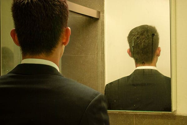 back of a man's head in a suit reflected in a mirror