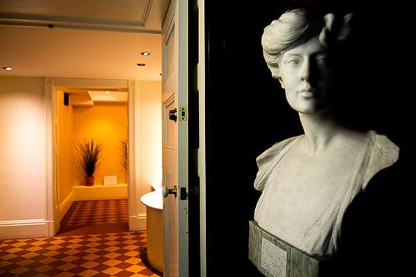 White marble bust of a woman in front of a hallway