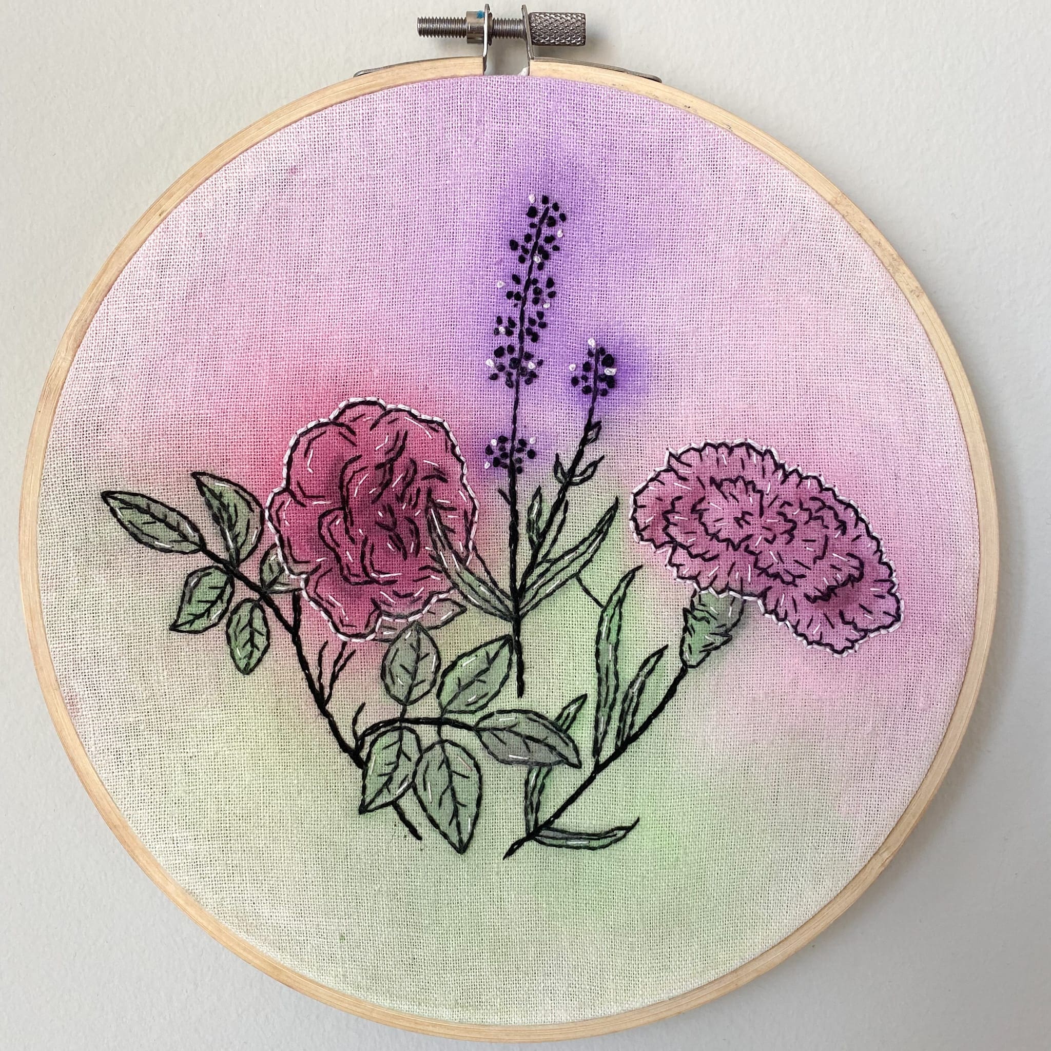 cross-stitch of pink and purple flowers on a hoop