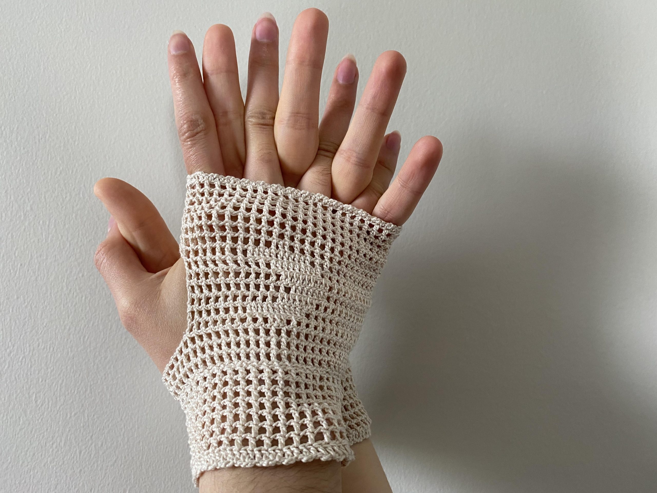 two interlaced hands inside fingerless hand covering