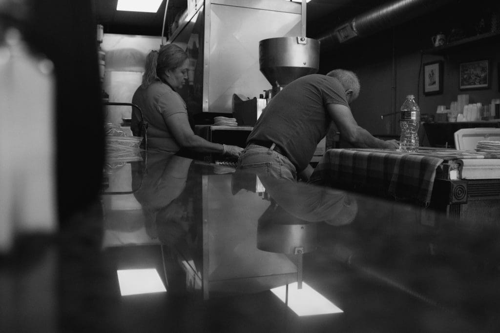 a woman standing behind a man leaning on a counter