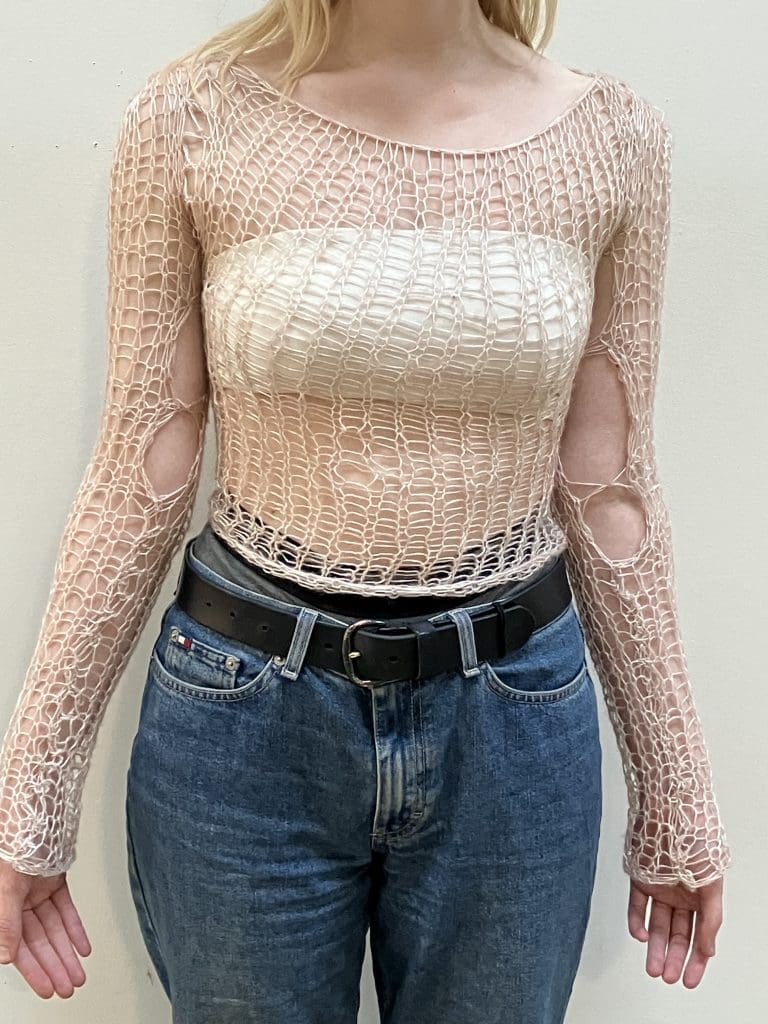 girl wearing a hand knitted tan fishnet sweater.