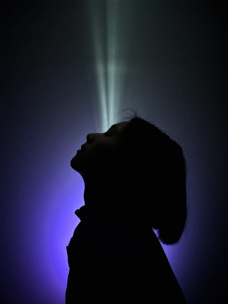 a silhouetted girl in front of a blue light and black background