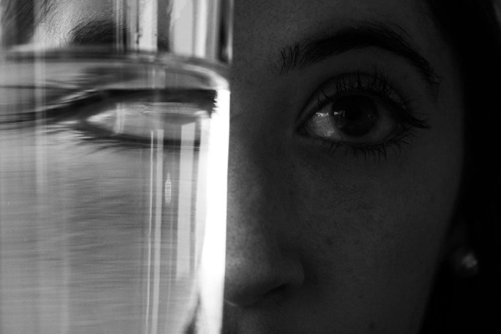 a girl's face obstructed by a glass of water, in black and white