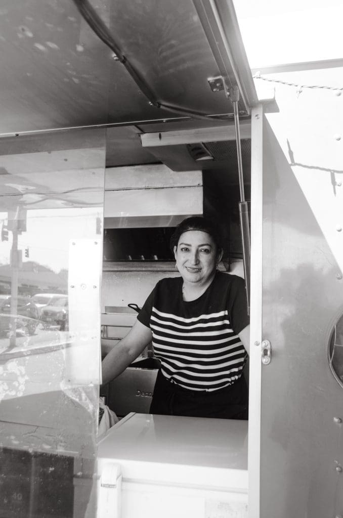 a woman smiling standing inside a food truck