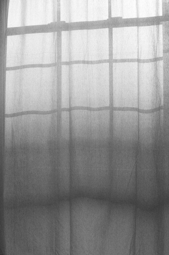 a window curtain with shadows of a window frame, in black and white