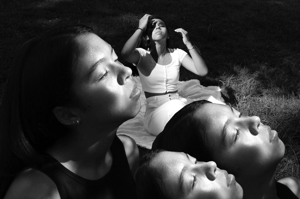 a girl duplicated multiple times staring up at the sun, in black and white