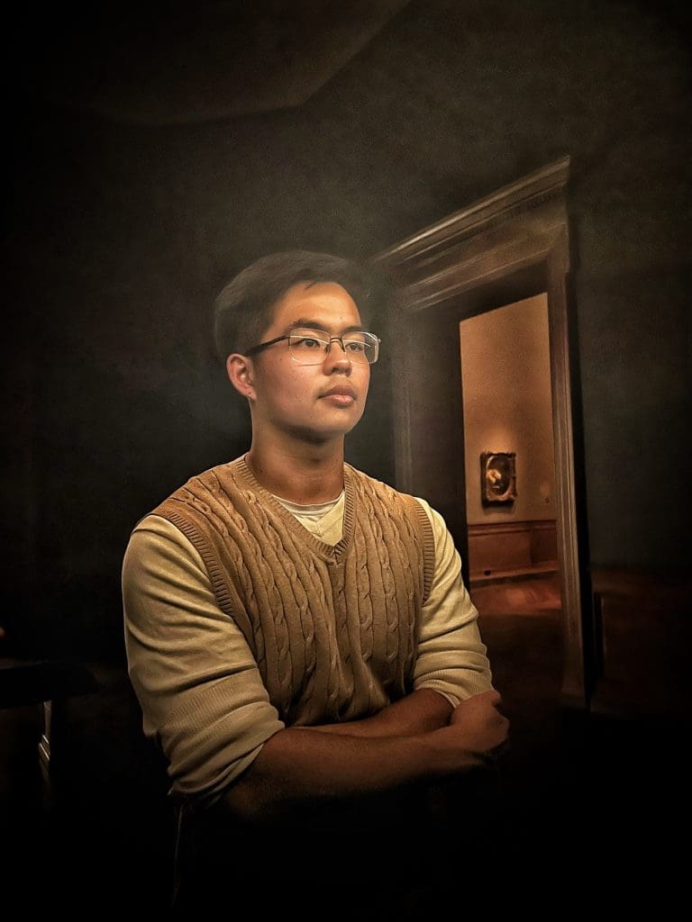 a man with short hair glasses and a tan sweater vest at the baltimore museum of art