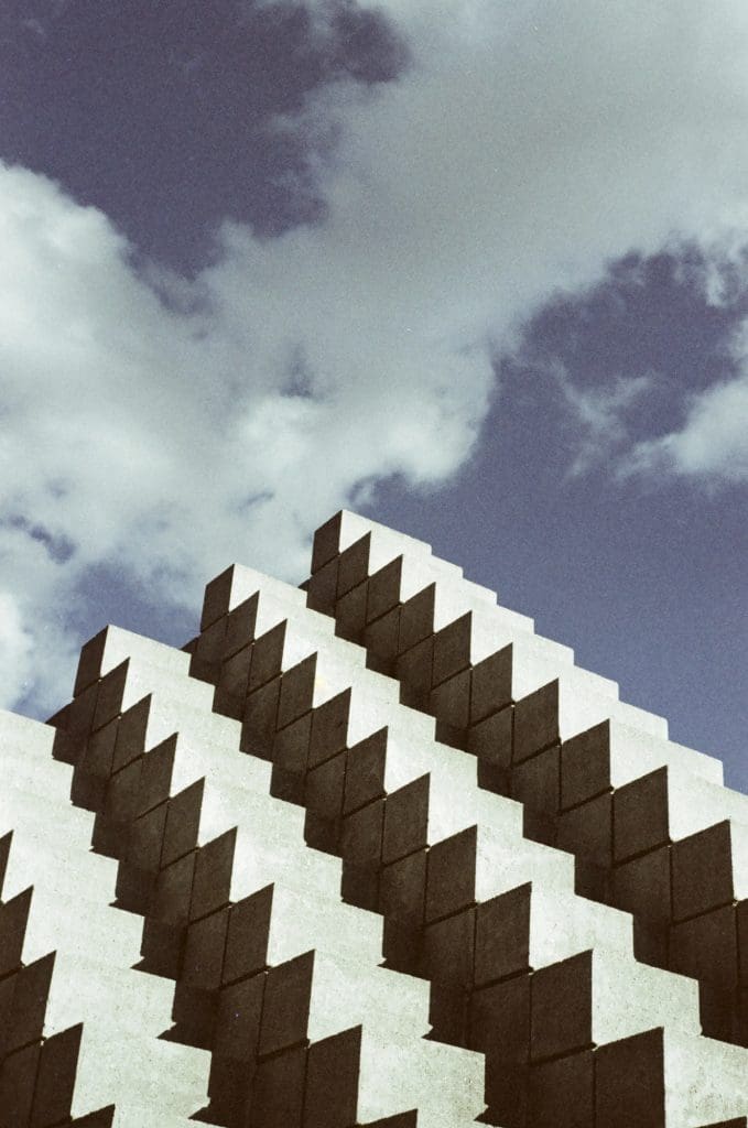 a cement pyramid-shaped building with a cloudy sky in the background