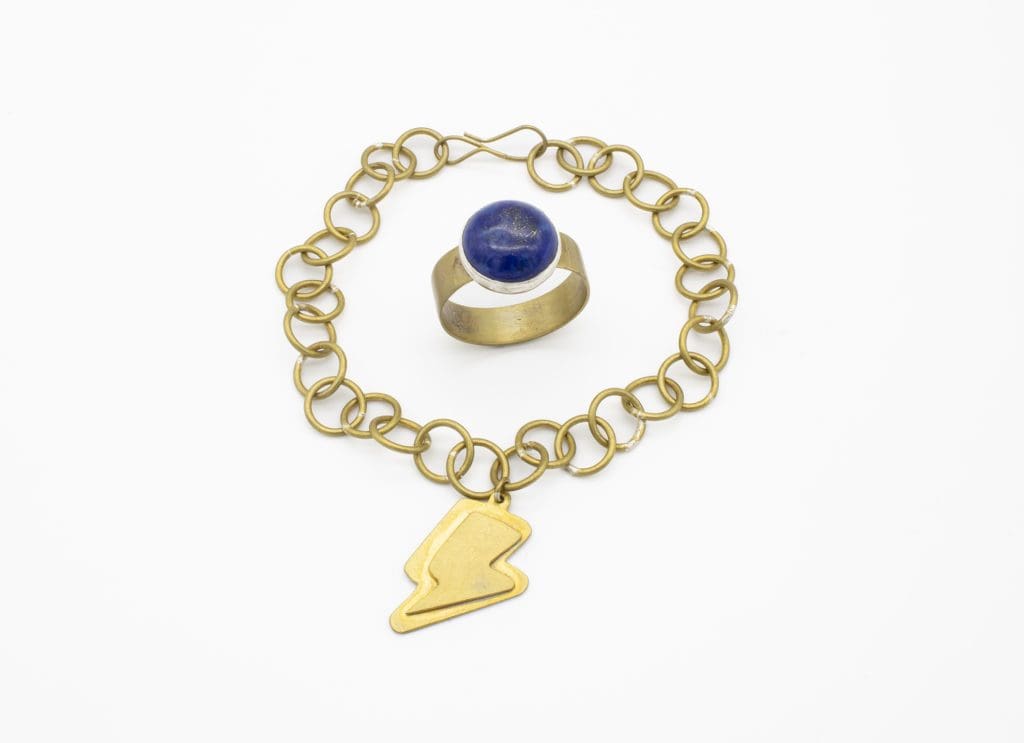 gold necklace with lightning bolt and gold ring with blue stone