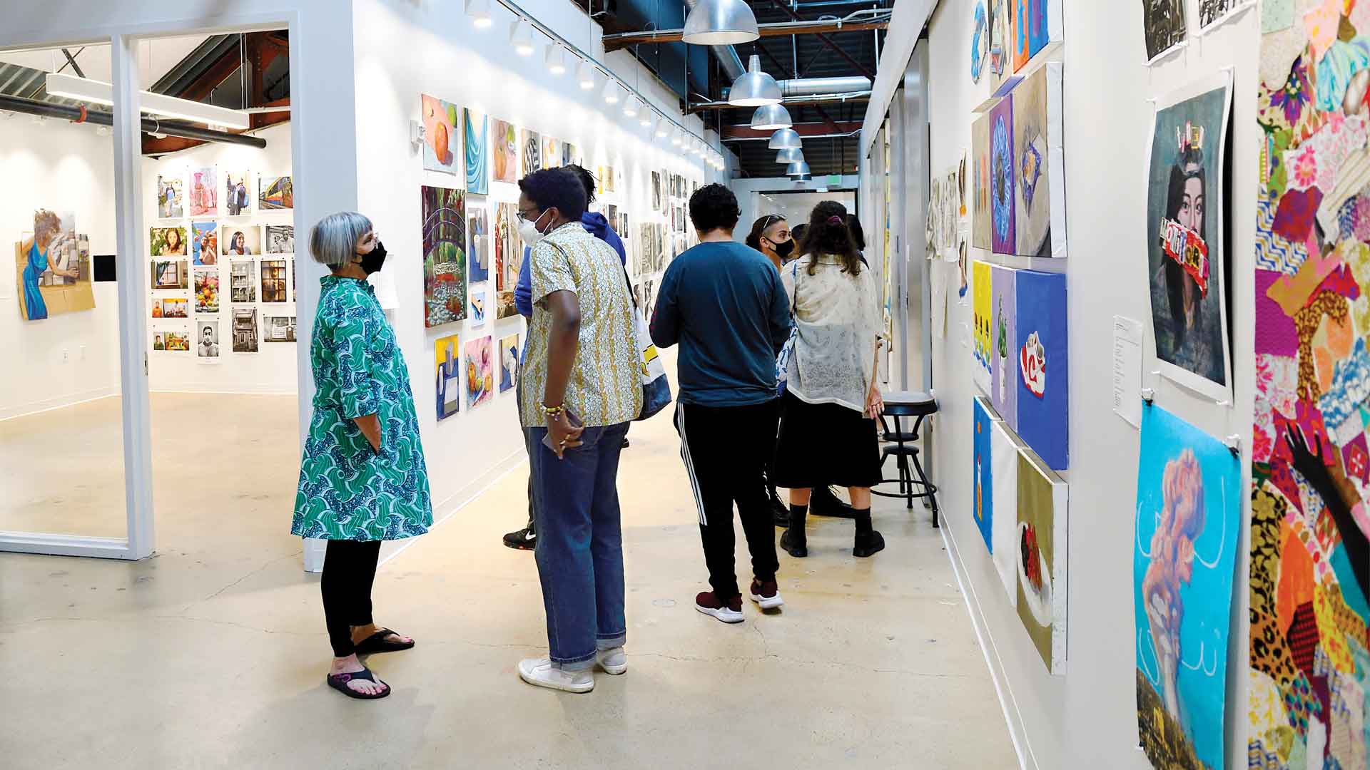 students standing in the hallway of the center for visual arts surrounded by artwork hanging all over the walls