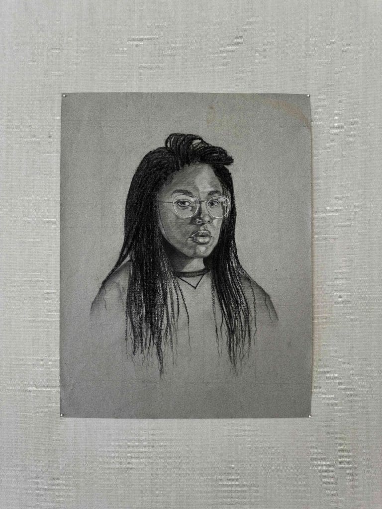 charcoal self portrait of a girl hung on wall
