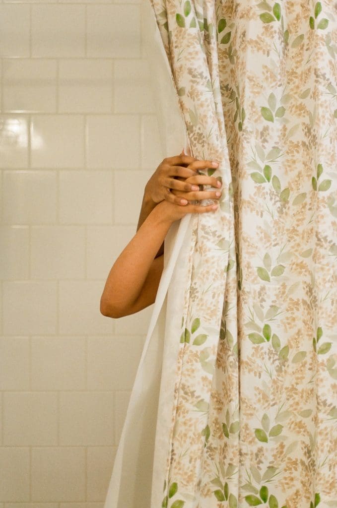Two hands clasped together holding a shower curtain with a leaf print