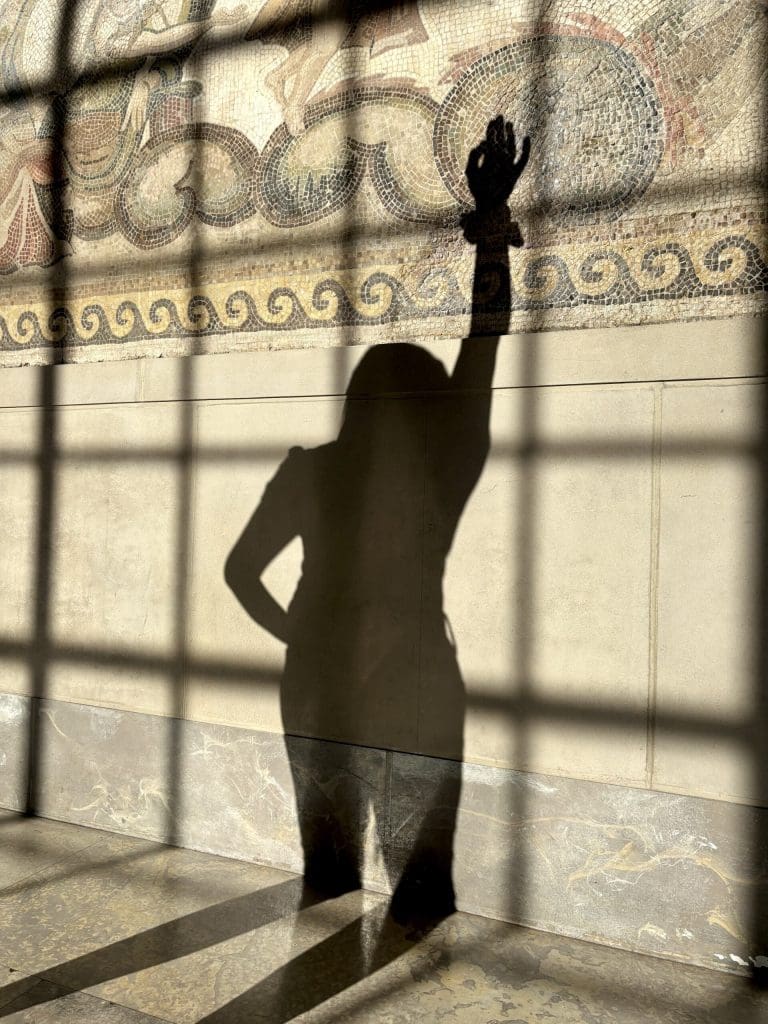 a shadow of a person holding one and up and the other on their hip