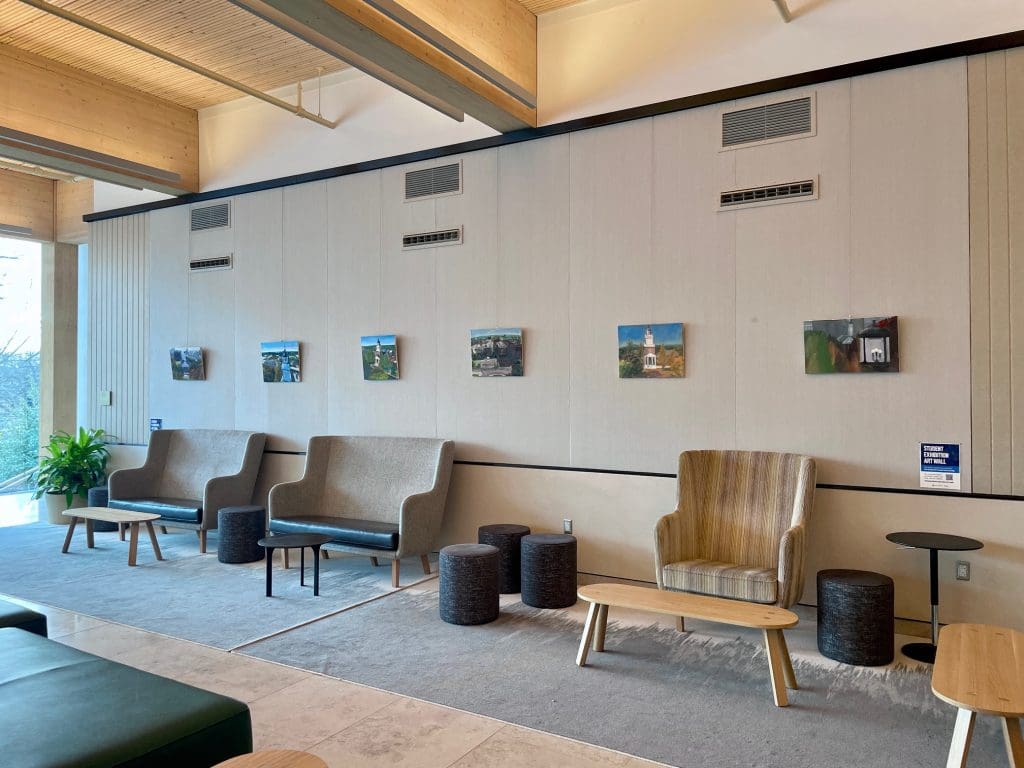 paintings on a tan wall behind couches