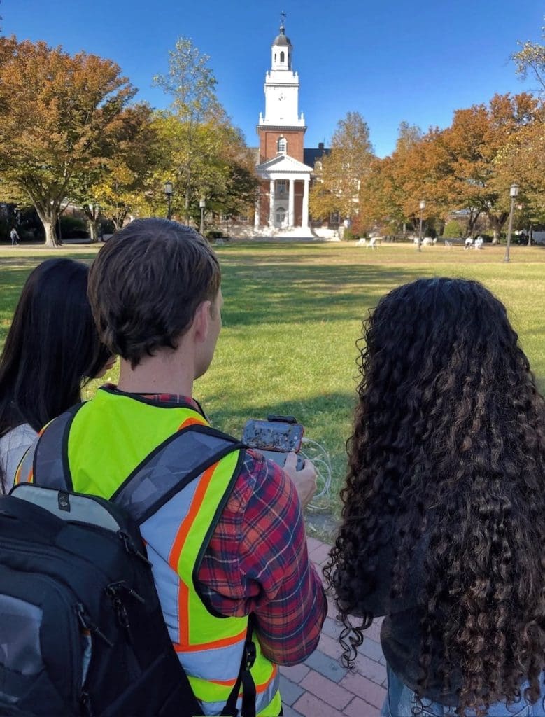 students looking at drone camera with drone operator 