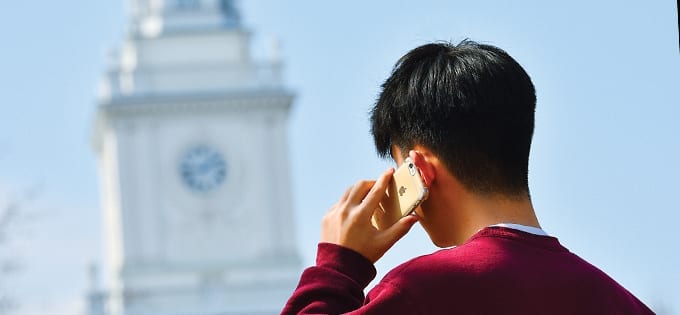 student on cellphone in front of Gilman Hall