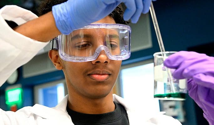 Male student pipetting liquid into beaker