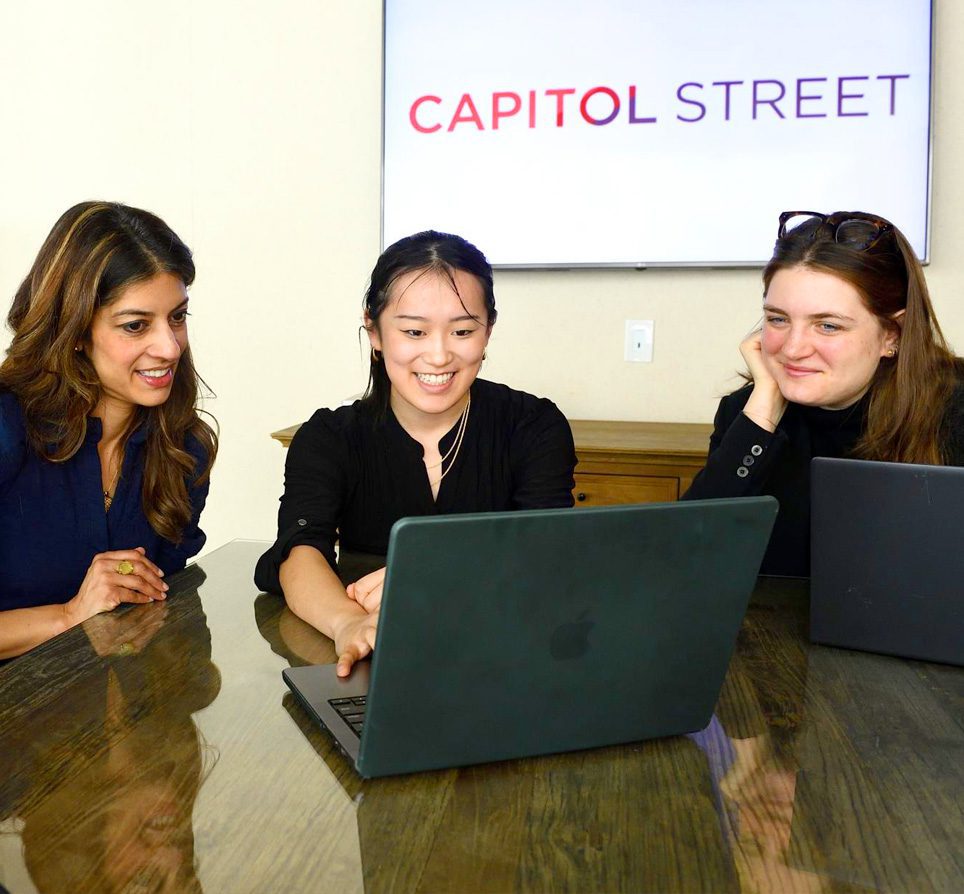 Alumna mentor with two students looking at laptop at Capitol Street in Washington, D.C.