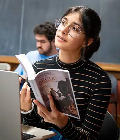 student listening in class holding an open book