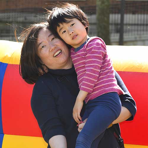 Parent holding young child in front of colorful background.