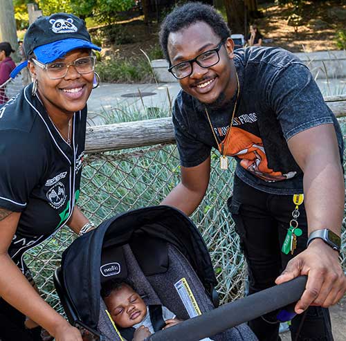 Smiling parents with baby in stroller at the Maryland Zoo.