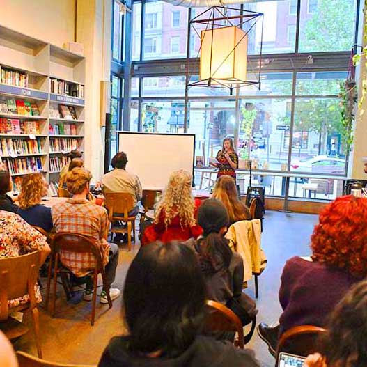 A view from the back of the audience listening to a reading at Bird in Hand, a bookstore that hosts events near campus in Charles Village.