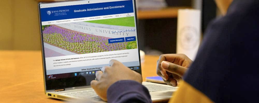 over shoulder view of laptop screen with graduate admissions page showing