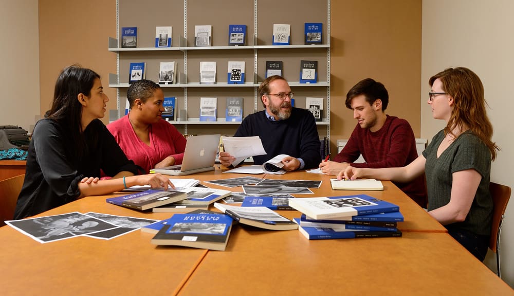 Professor David Yezzi in discussion with four students.